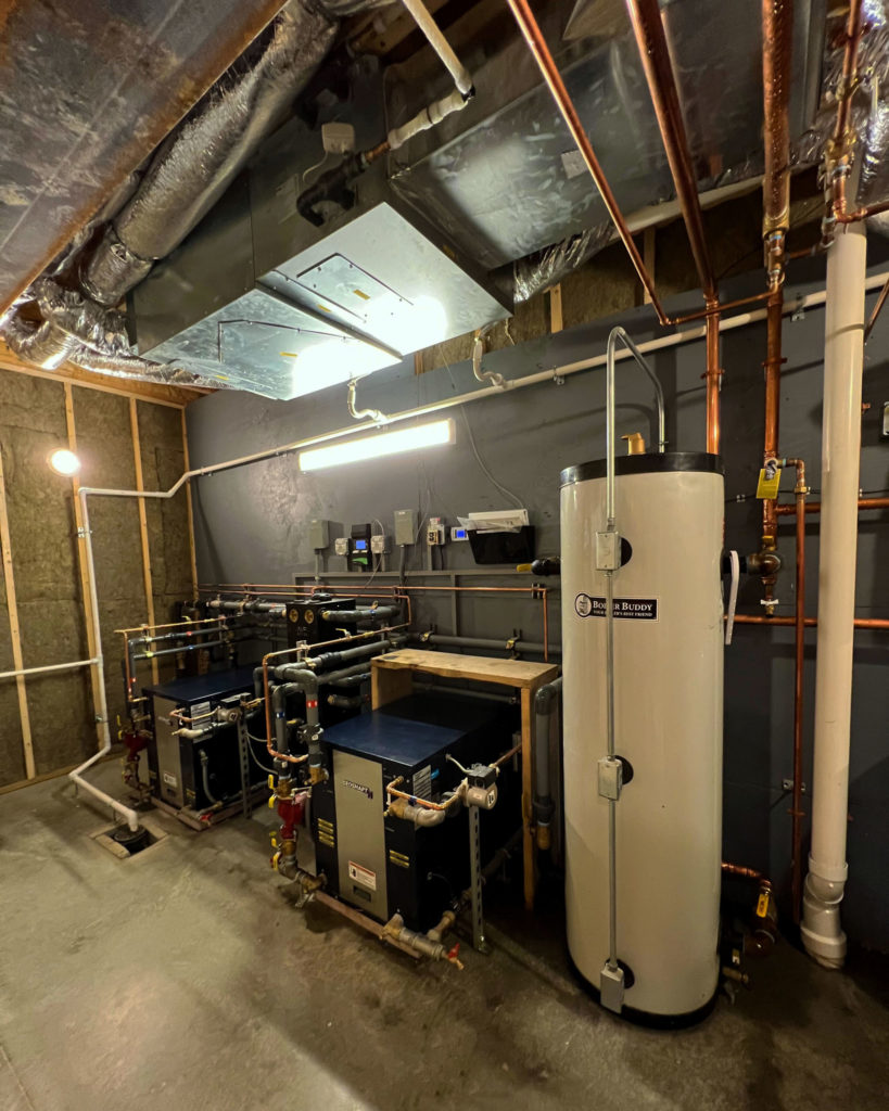 Mechanical room that utilizes two geothermal heat pumps to provide hydronic heating and cooling.