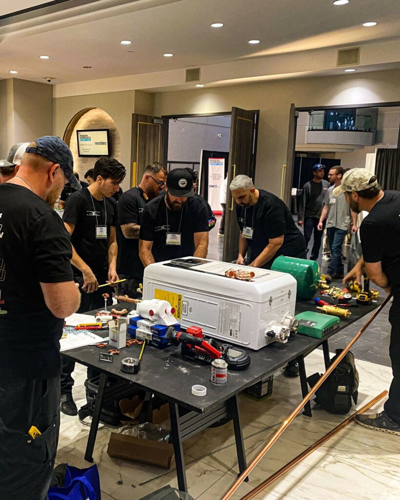 Hydronic installers working on a mechanical room at the Modern Hydronics Summit.