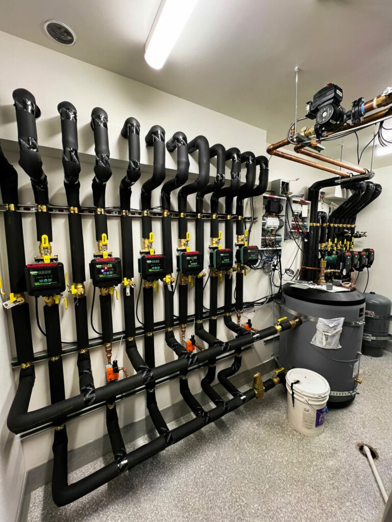 Mechanical room with three mixing stations for hydronic heating and cooling via a radiant floor.